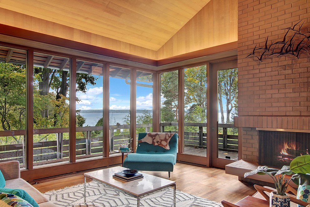 Large midcentury formal open concept living room in Seattle with brown walls, medium hardwood floors, a standard fireplace, a brick fireplace surround and brown floor.