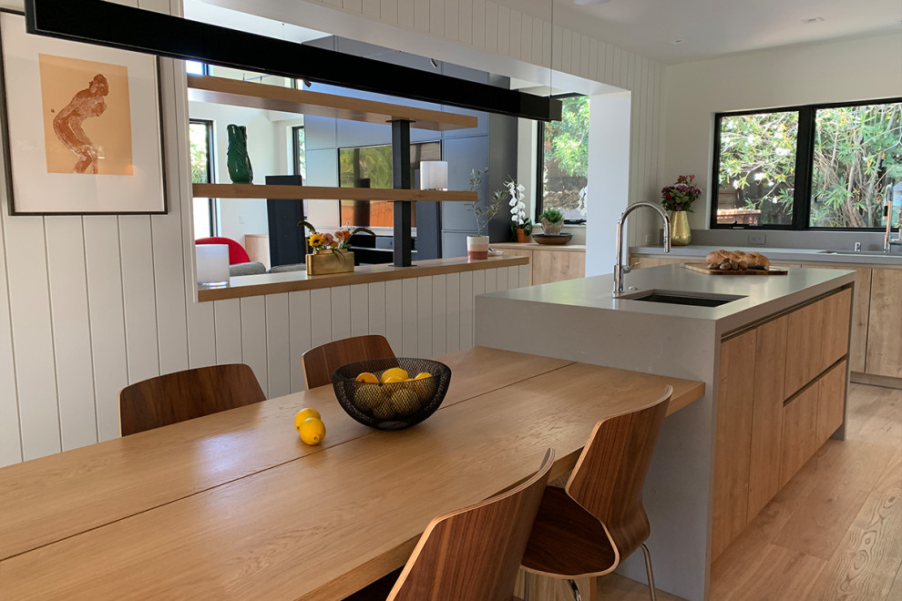 Foto på ett mellanstort minimalistiskt grå kök, med en undermonterad diskho, släta luckor, svarta skåp, bänkskiva i koppar, grått stänkskydd, stänkskydd i sten, integrerade vitvaror, ljust trägolv, en köksö och brunt golv