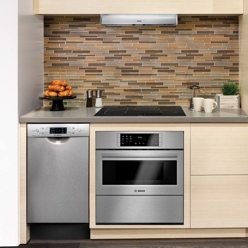 Example of a small minimalist single-wall dark wood floor enclosed kitchen design in Houston with flat-panel cabinets, light wood cabinets, solid surface countertops, multicolored backsplash, glass tile backsplash and stainless steel appliances