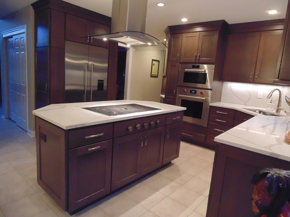 Photo of a mid-sized transitional u-shaped eat-in kitchen in New York with an undermount sink, recessed-panel cabinets, dark wood cabinets, quartz benchtops, beige splashback, stainless steel appliances, cement tiles, with island, beige floor and beige benchtop.