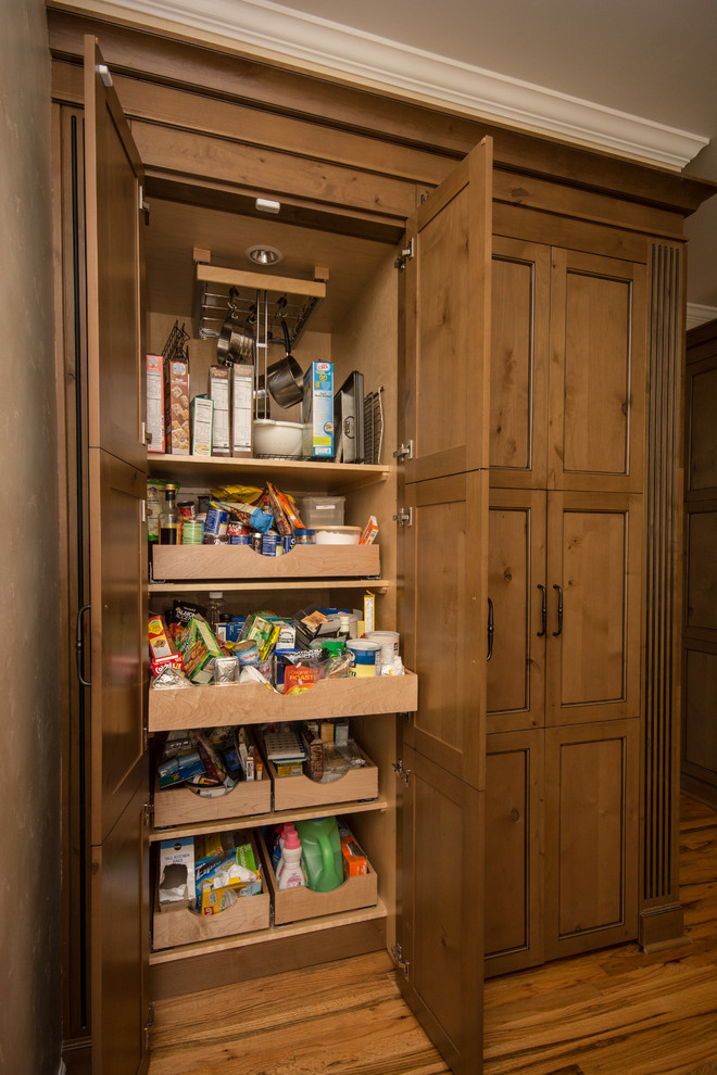 Inspiration for a large traditional kitchen pantry in Atlanta with medium wood cabinets, medium hardwood floors, brown floor, a farmhouse sink, shaker cabinets, granite benchtops, beige splashback, stone tile splashback, stainless steel appliances and with island.