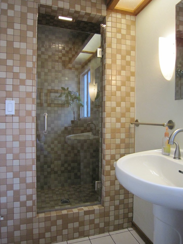 Photo of a mid-sized beach style 3/4 bathroom in Orange County with a pedestal sink, white tile, beige tile, brown tile, light wood cabinets, an alcove shower, a two-piece toilet, mosaic tile, white walls and ceramic floors.