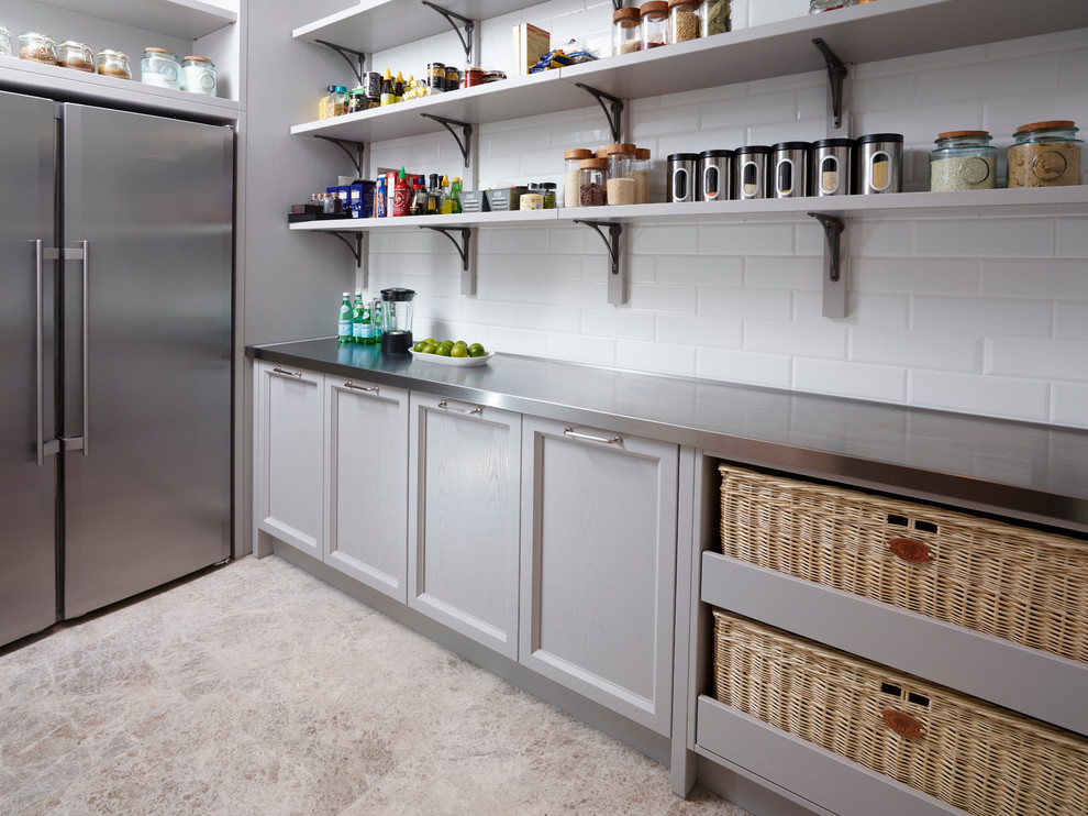 Inspiration for a traditional l-shaped kitchen pantry in London with shaker cabinets, grey cabinets, stainless steel benchtops, white splashback, subway tile splashback, stainless steel appliances, limestone floors and no island.
