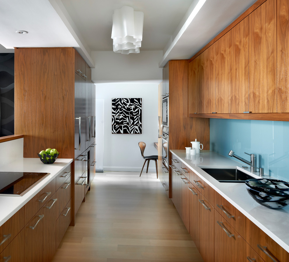 Design ideas for a large contemporary galley kitchen in Chicago with an undermount sink, flat-panel cabinets, medium wood cabinets, quartz benchtops, blue splashback, glass sheet splashback, stainless steel appliances and light hardwood floors.