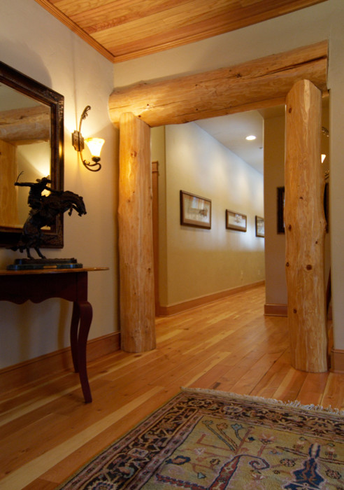 Example of a large mountain style medium tone wood floor hallway design in Denver with beige walls