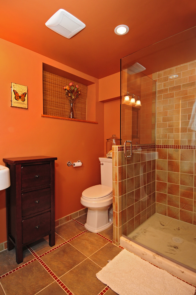 Photo of an arts and crafts 3/4 bathroom in Seattle with a pedestal sink, furniture-like cabinets, dark wood cabinets, a two-piece toilet, multi-coloured tile, ceramic tile, orange walls and porcelain floors.