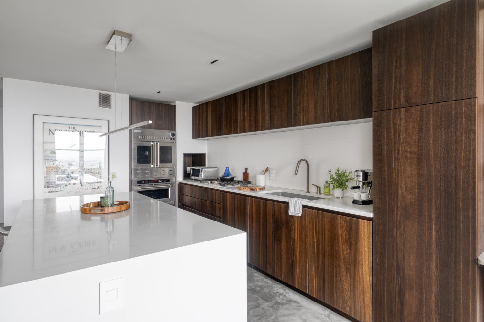 Mid-sized minimalist l-shaped concrete floor and gray floor open concept kitchen photo in New York with an undermount sink, flat-panel cabinets, dark wood cabinets, quartz countertops, white backsplash, porcelain backsplash, stainless steel appliances, an island and white countertops