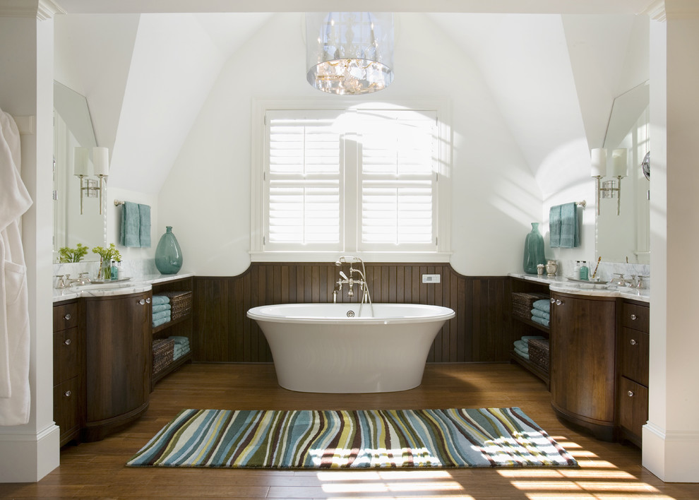 This is an example of a large beach style master bathroom in Boston with a freestanding tub, marble benchtops, flat-panel cabinets, dark wood cabinets, white walls, medium hardwood floors, an undermount sink and brown floor.