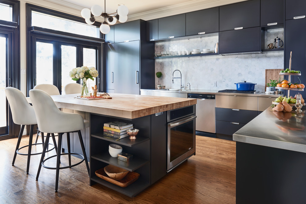 This is an example of a large modern u-shaped separate kitchen with an integrated sink, flat-panel cabinets, black cabinets, stainless steel benchtops, grey splashback, marble splashback, panelled appliances, medium hardwood floors, with island and brown floor.