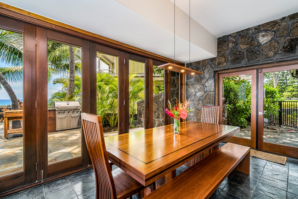 Design ideas for a mid-sized tropical dining room in Hawaii with white walls, slate floors and black floor.