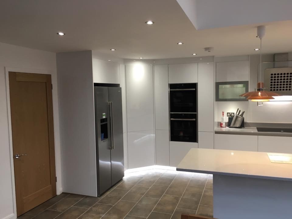 Inspiration for a large contemporary u-shaped eat-in kitchen in Cardiff with an integrated sink, flat-panel cabinets, white cabinets, quartzite benchtops, glass sheet splashback, stainless steel appliances and no island.