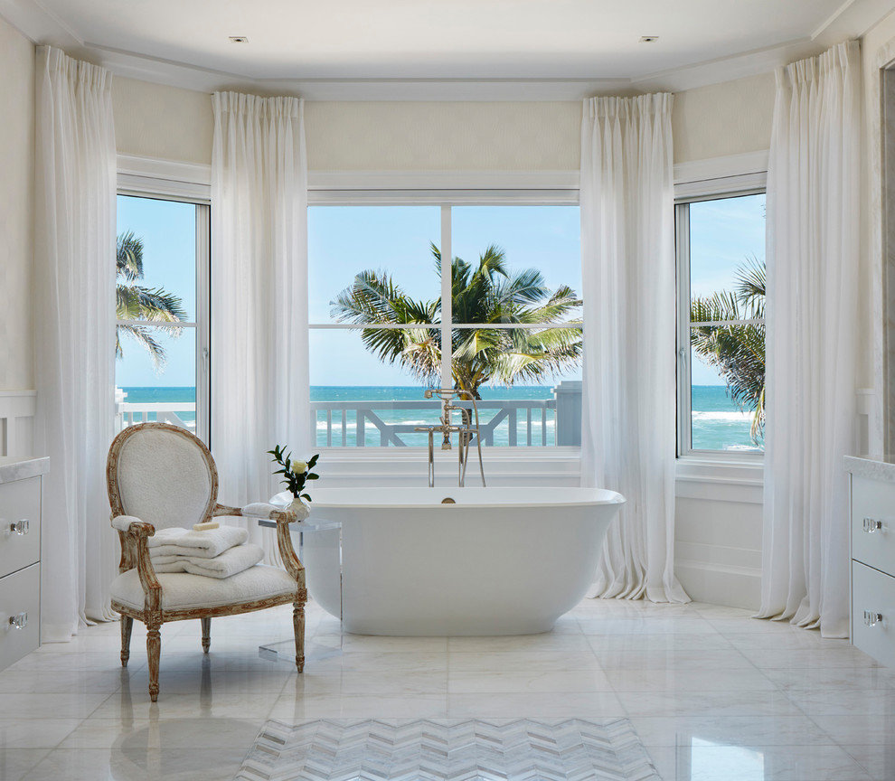 This is an example of a beach style master bathroom in Miami with a freestanding tub and white floor.