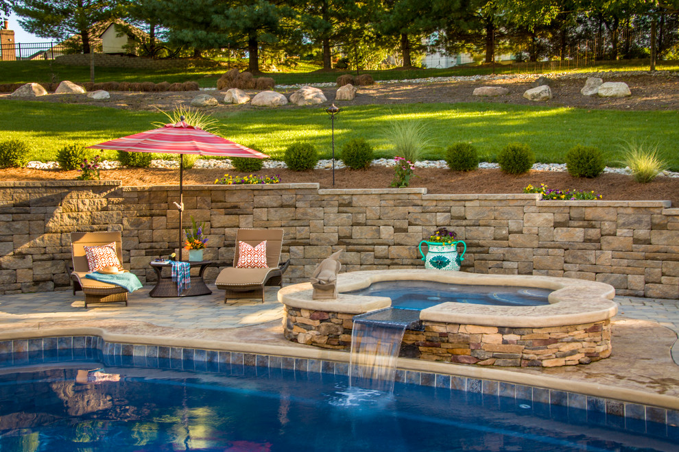 Inspiration for a large traditional backyard custom-shaped natural pool in Cincinnati with a hot tub and natural stone pavers.