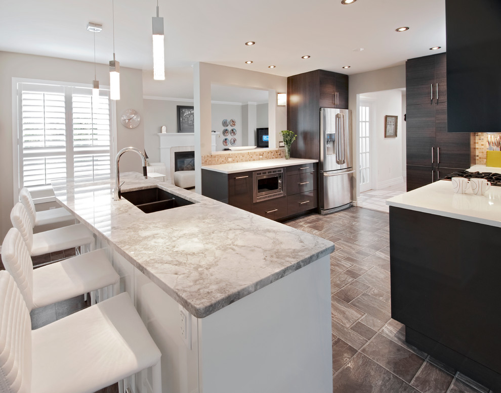 Photo of a contemporary galley kitchen in Ottawa with a double-bowl sink, dark wood cabinets, marble benchtops, stainless steel appliances, flat-panel cabinets, beige splashback and mosaic tile splashback.