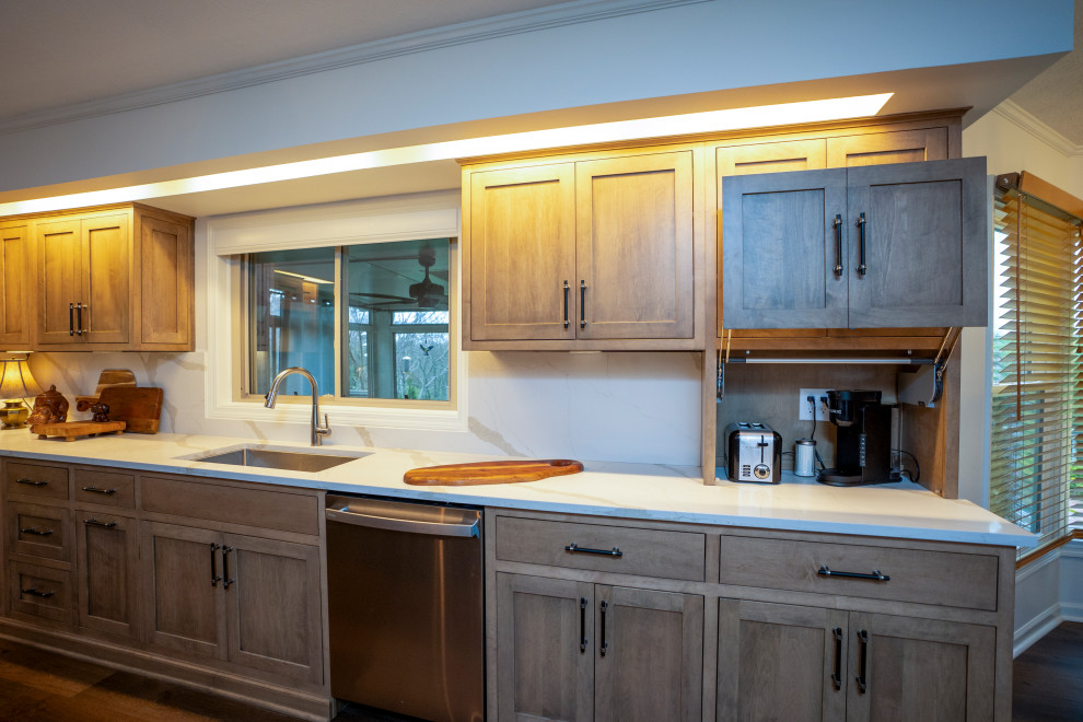 Large transitional l-shaped medium tone wood floor and brown floor eat-in kitchen photo with a single-bowl sink, shaker cabinets, medium tone wood cabinets, quartz countertops, white backsplash, quartz backsplash, stainless steel appliances, an island and white countertops