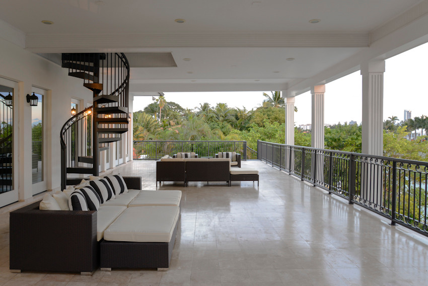 This is an example of a large transitional backyard deck in Miami with a roof extension.