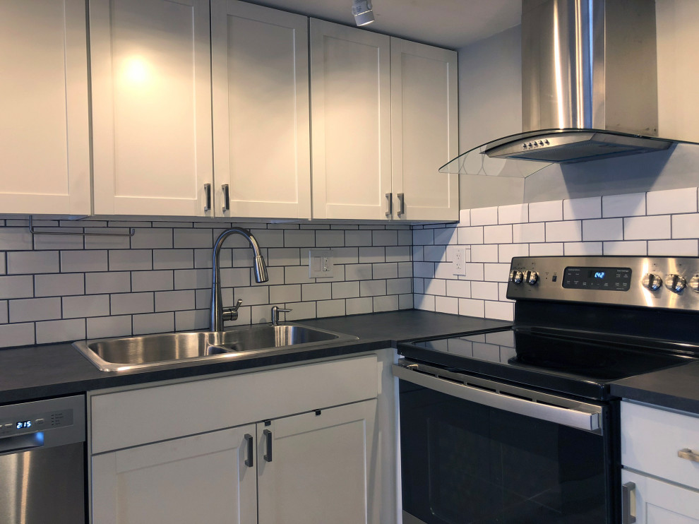 Small modern l-shaped eat-in kitchen in Boston with a double-bowl sink, recessed-panel cabinets, laminate benchtops, subway tile splashback, stainless steel appliances, laminate floors, no island, grey floor and grey benchtop.