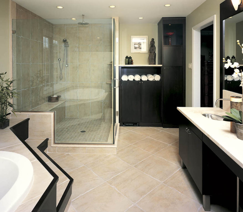 This is an example of a mid-sized contemporary master bathroom in Philadelphia with flat-panel cabinets, black cabinets, a drop-in tub, a corner shower, brown tile, travertine, beige walls, travertine floors, an undermount sink, beige floor, a hinged shower door and white benchtops.