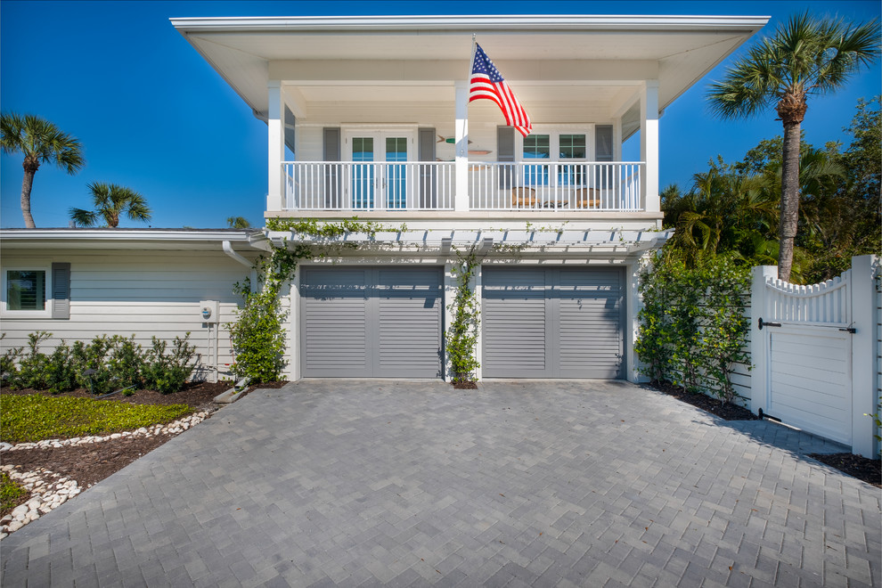Photo of a mid-sized beach style two-storey white house exterior in Tampa with vinyl siding, a flat roof and a shingle roof.