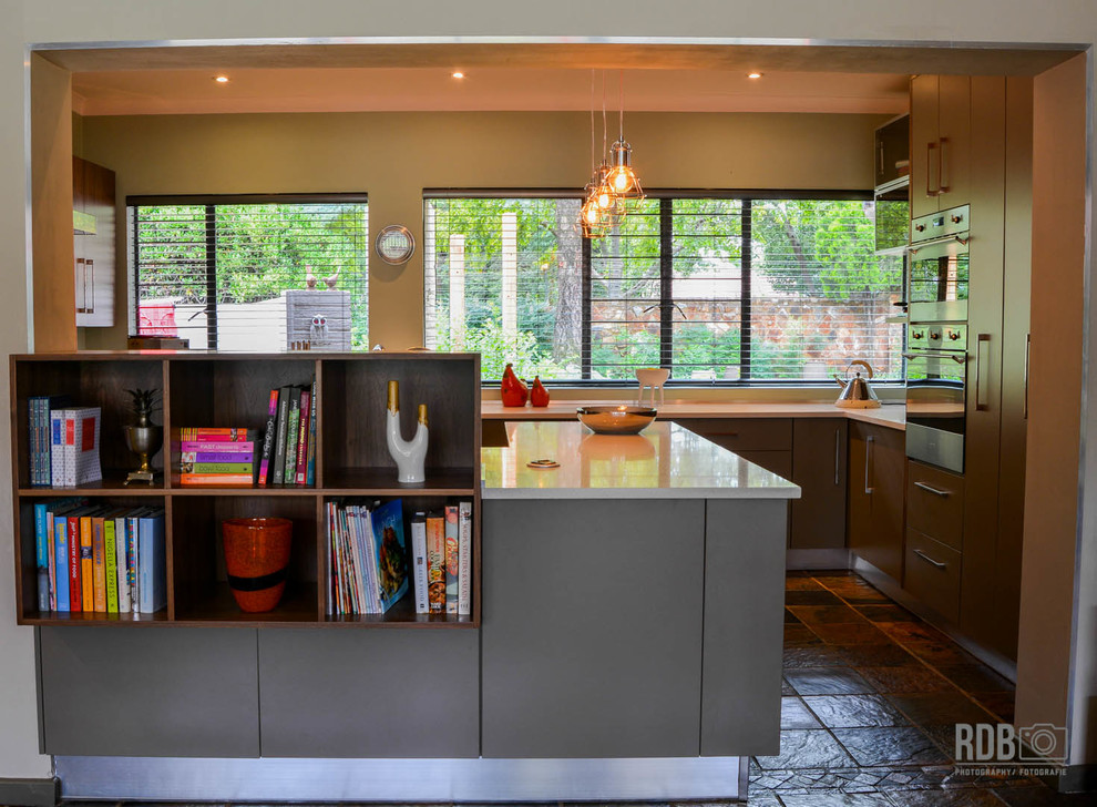 Enclosed kitchen - mid-sized rustic u-shaped slate floor enclosed kitchen idea with a drop-in sink, flat-panel cabinets, green cabinets, quartz countertops, red backsplash, glass sheet backsplash, stainless steel appliances and an island