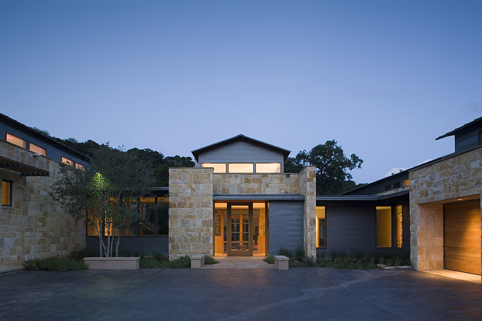 Photo of a large contemporary two-storey grey exterior in Austin with stone veneer.