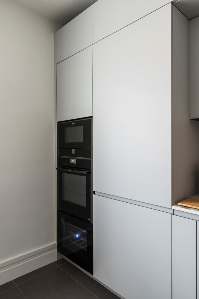 Geschlossene, Kleine Moderne Küche in L-Form mit Unterbauwaschbecken, flächenbündigen Schrankfronten, Porzellan-Bodenfliesen und grauem Boden in Mailand