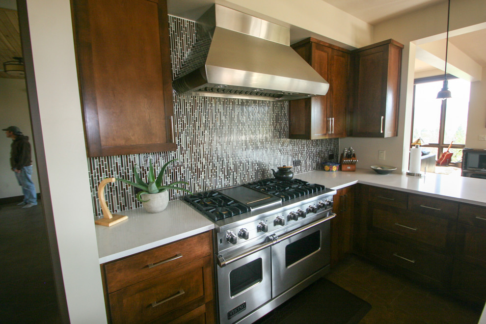Mid-sized transitional u-shaped open concept kitchen photo with shaker cabinets, dark wood cabinets, solid surface countertops, brown backsplash, matchstick tile backsplash, stainless steel appliances and white countertops