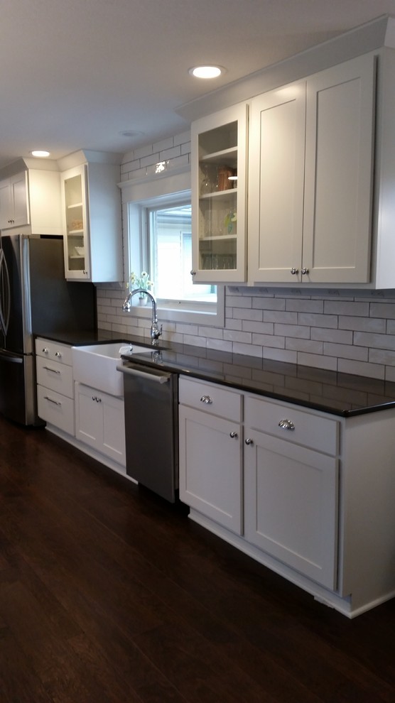 Eat-in kitchen - transitional galley dark wood floor eat-in kitchen idea with white cabinets, granite countertops, white backsplash, subway tile backsplash and stainless steel appliances