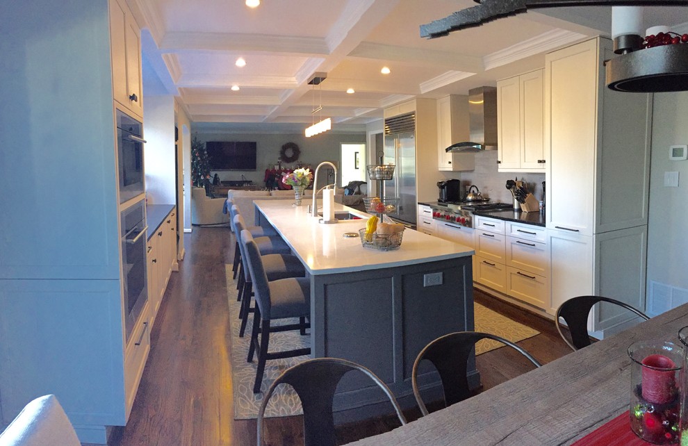 Large transitional galley open plan kitchen in Baltimore with white cabinets, quartz benchtops, grey splashback, porcelain splashback, stainless steel appliances, with island, a single-bowl sink, flat-panel cabinets, dark hardwood floors, brown floor and white benchtop.
