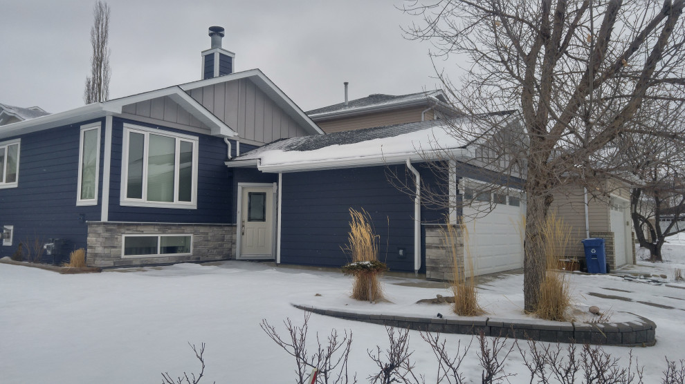 Photo of a mid-sized traditional one-storey blue house exterior in Calgary with concrete fiberboard siding and board and batten siding.