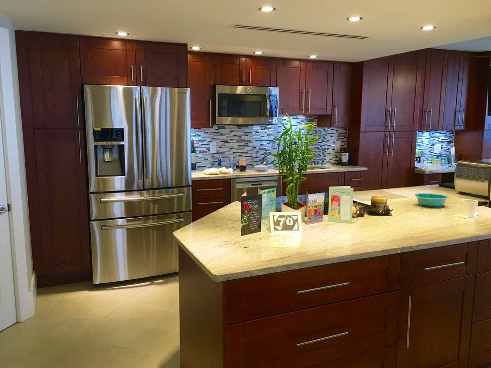 Example of a mid-sized transitional single-wall beige floor kitchen design in Miami with an undermount sink, shaker cabinets, medium tone wood cabinets, stainless steel appliances, an island, limestone countertops, gray backsplash and matchstick tile backsplash