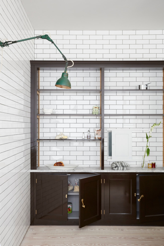 Inspiration for a transitional kitchen in London with open cabinets, white splashback, subway tile splashback and light hardwood floors.