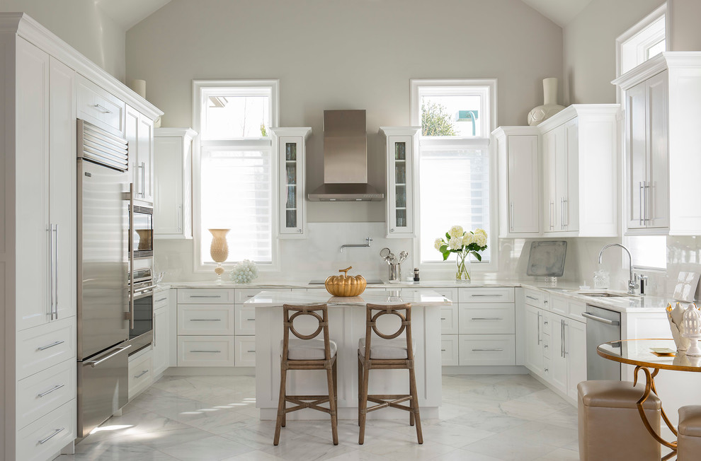 Photo of a mediterranean u-shaped eat-in kitchen in Dallas with an undermount sink, shaker cabinets, white cabinets, white splashback, stainless steel appliances, with island and marble floors.