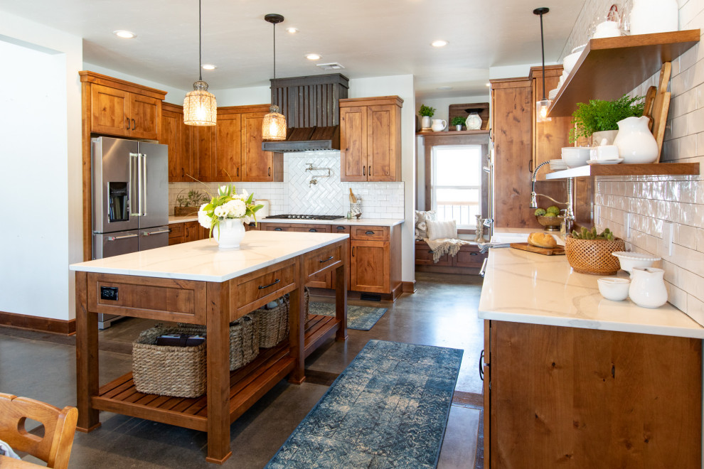 This is an example of a large country u-shaped eat-in kitchen in Portland with a farmhouse sink, shaker cabinets, medium wood cabinets, quartz benchtops, white splashback, subway tile splashback, stainless steel appliances, concrete floors, with island, grey floor and white benchtop.