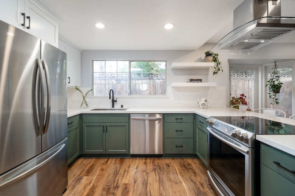 This is an example of a mid-sized midcentury u-shaped eat-in kitchen in Los Angeles with a single-bowl sink, shaker cabinets, green cabinets, quartz benchtops, yellow splashback, subway tile splashback, stainless steel appliances, vinyl floors, a peninsula, brown floor and white benchtop.