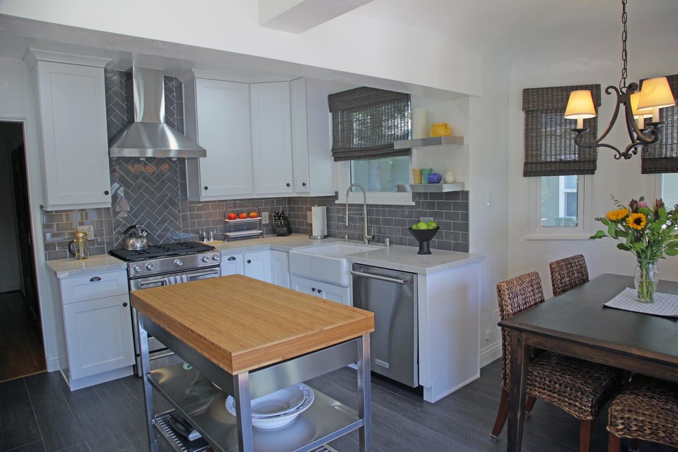 Photo of a small transitional l-shaped eat-in kitchen in Los Angeles with a farmhouse sink, shaker cabinets, white cabinets, grey splashback, subway tile splashback, stainless steel appliances and with island.