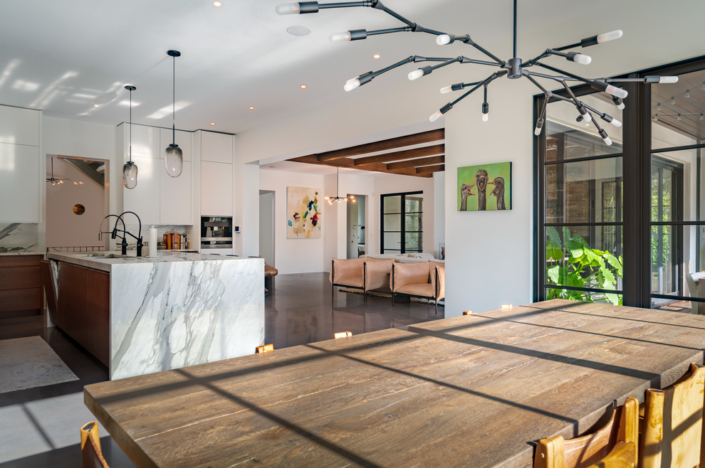 Example of a concrete floor and gray floor kitchen pantry design with an undermount sink, flat-panel cabinets, white cabinets, marble countertops, gray backsplash, marble backsplash, stainless steel appliances, an island and gray countertops