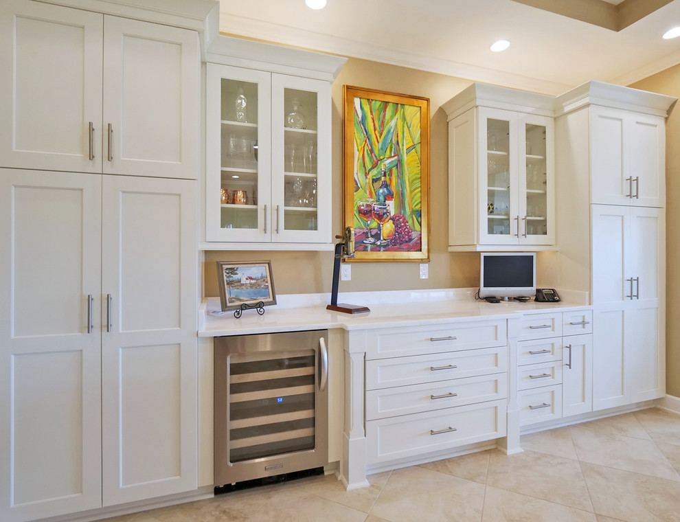 This is an example of an expansive tropical u-shaped eat-in kitchen in Jacksonville with an undermount sink, beaded inset cabinets, white cabinets, quartzite benchtops, beige splashback, marble splashback, stainless steel appliances, porcelain floors, multiple islands, beige floor and white benchtop.