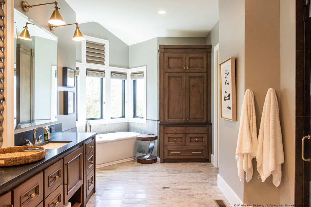 Photo of a large transitional master bathroom in Salt Lake City with dark wood cabinets, a freestanding tub, porcelain floors, a drop-in sink, grey floor, a hinged shower door, black benchtops, a double vanity, a built-in vanity, beaded inset cabinets, black and white tile and grey walls.