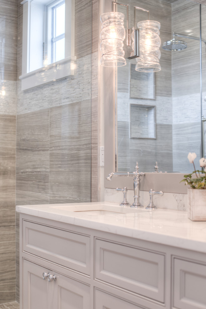 Example of a mid-sized transitional master beige tile, brown tile, white tile and porcelain tile porcelain tile and multicolored floor alcove shower design with shaker cabinets, white cabinets, beige walls, an undermount sink, quartz countertops and a hinged shower door