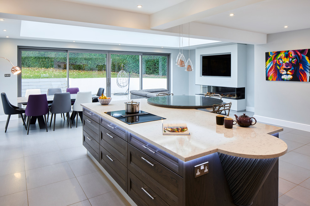 Inspiration for a mid-sized modern l-shaped open plan kitchen in Surrey with black splashback, black appliances, medium hardwood floors, with island and beige benchtop.