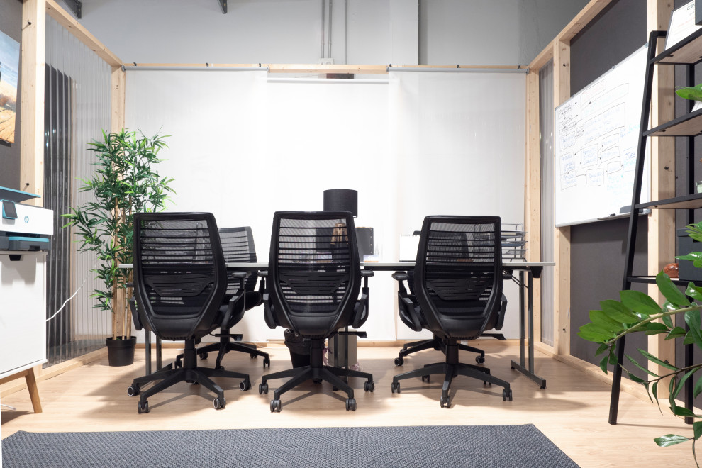 Cette photo montre un très grand bureau industriel avec un mur gris, parquet clair, un bureau indépendant et un sol beige.