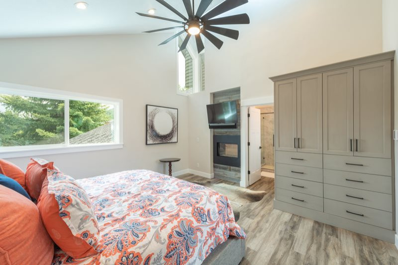 Inspiration for a mid-sized country master bedroom in Salt Lake City with beige walls, laminate floors, a two-sided fireplace, a metal fireplace surround, multi-coloured floor and vaulted.