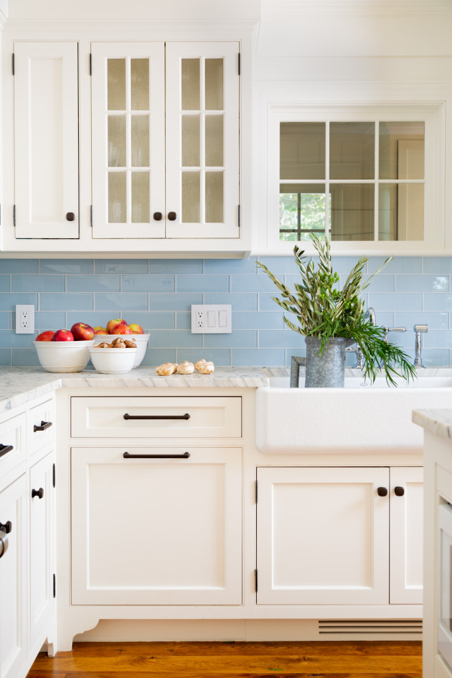 Idéer för mellanstora maritima vitt u-kök, med vita skåp, marmorbänkskiva, blått stänkskydd, stänkskydd i mosaik, mellanmörkt trägolv, en köksö och brunt golv