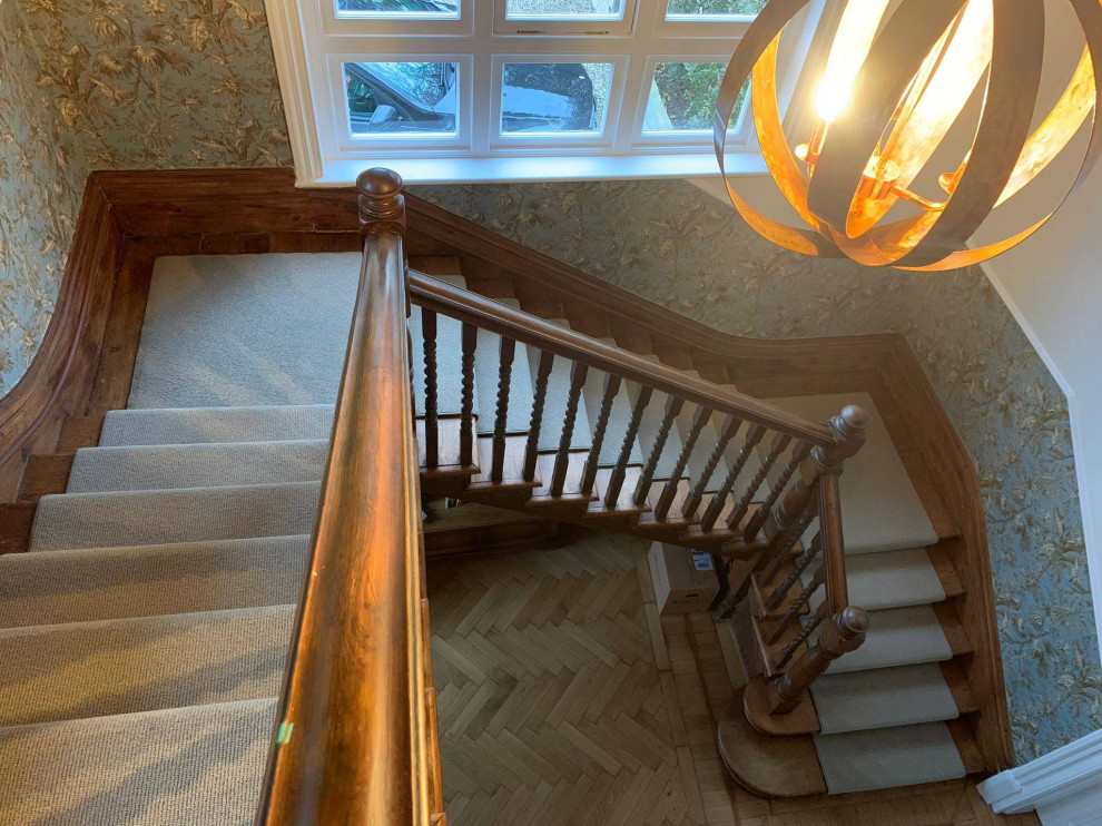 Inspiration for an expansive traditional carpeted u-shaped staircase in Surrey with wood railing and wallpaper.
