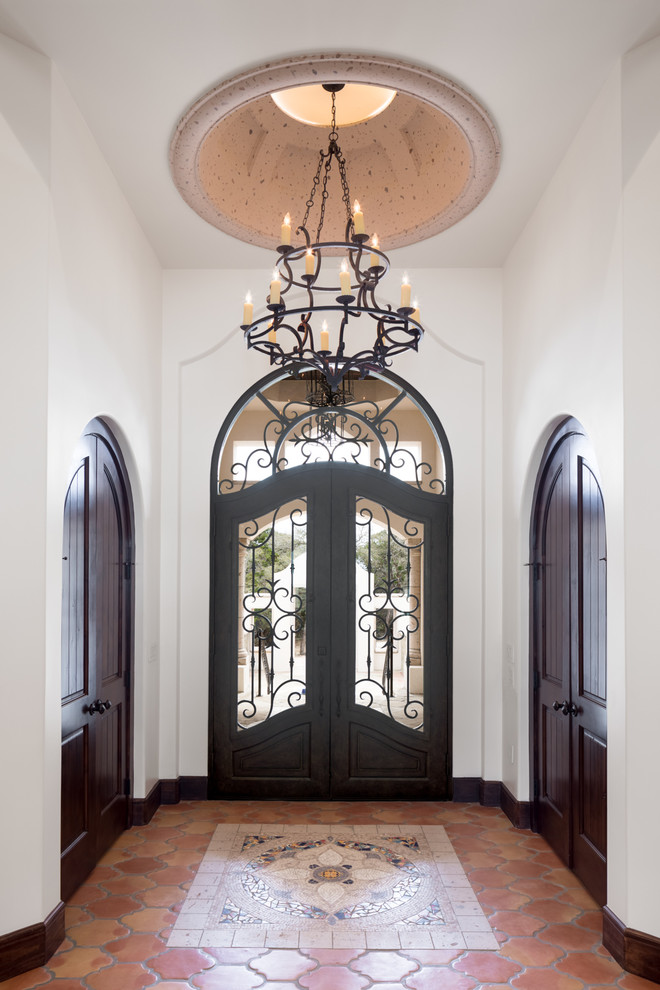 Photo of a mid-sized mediterranean foyer in Austin with white walls, ceramic floors, a double front door, a brown front door and multi-coloured floor.
