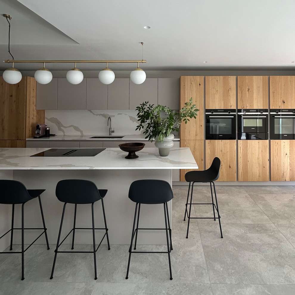 Modern inredning av ett stort linjärt kök och matrum, med en integrerad diskho, släta luckor, grå skåp, bänkskiva i koppar, stänkskydd i keramik, svarta vitvaror, cementgolv, en köksö och grått golv