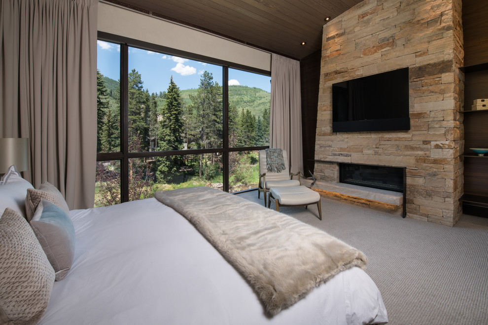 Design ideas for a large country master bedroom in Denver with brown walls, carpet, a ribbon fireplace, a stone fireplace surround and beige floor.
