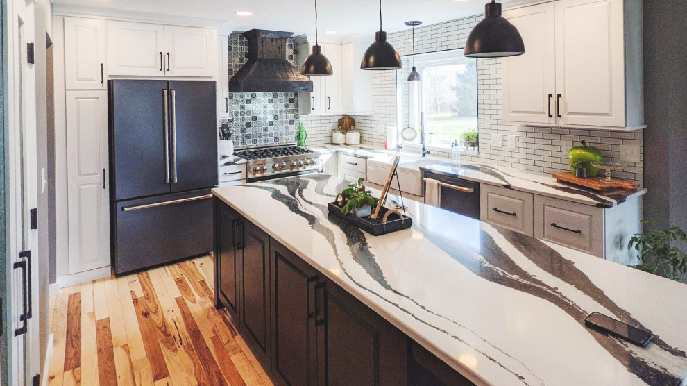 Transitional light wood floor kitchen photo in Chicago with a farmhouse sink, glass-front cabinets, white cabinets, quartzite countertops, white backsplash, subway tile backsplash, black appliances, an island and white countertops