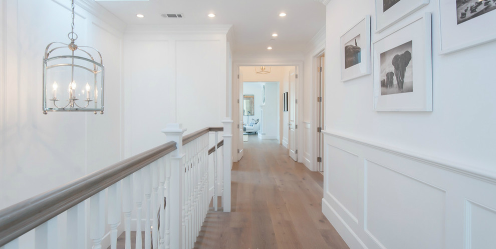 Photo of a large beach style hallway in Los Angeles with white walls and light hardwood floors.